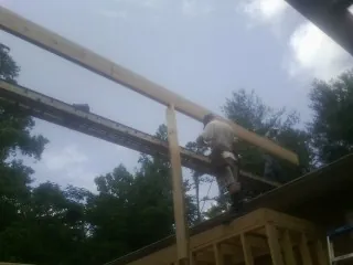 Carpenter setting a ridge beam over a new addition frame — Ice Dam Removal by Roofing Brothers in Sula