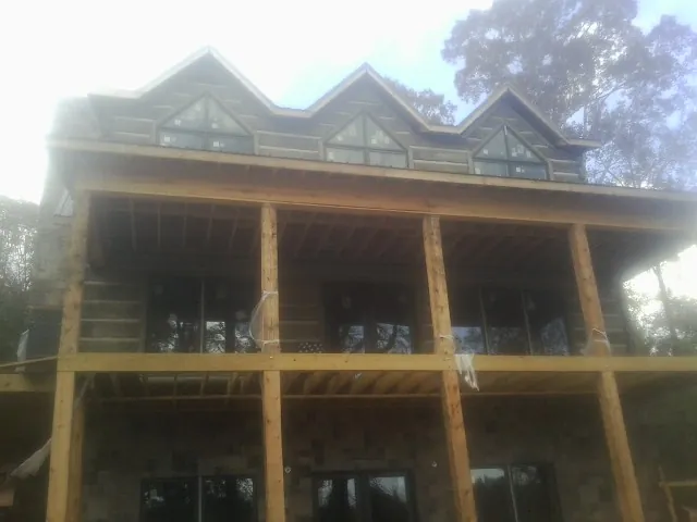 Dormers and porch framing on a large log home under construction — Roof Coating work by our crew in Sula