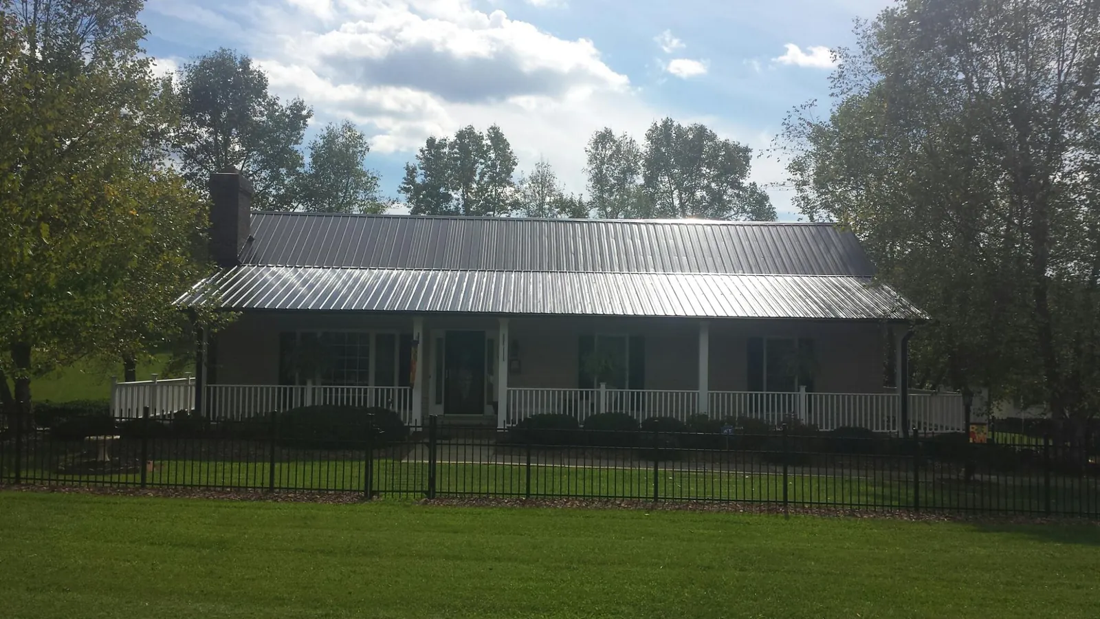 Gray metal roof on a brick ranch with a full width front porch — Gutter Guard Installation work by our crew in Sula