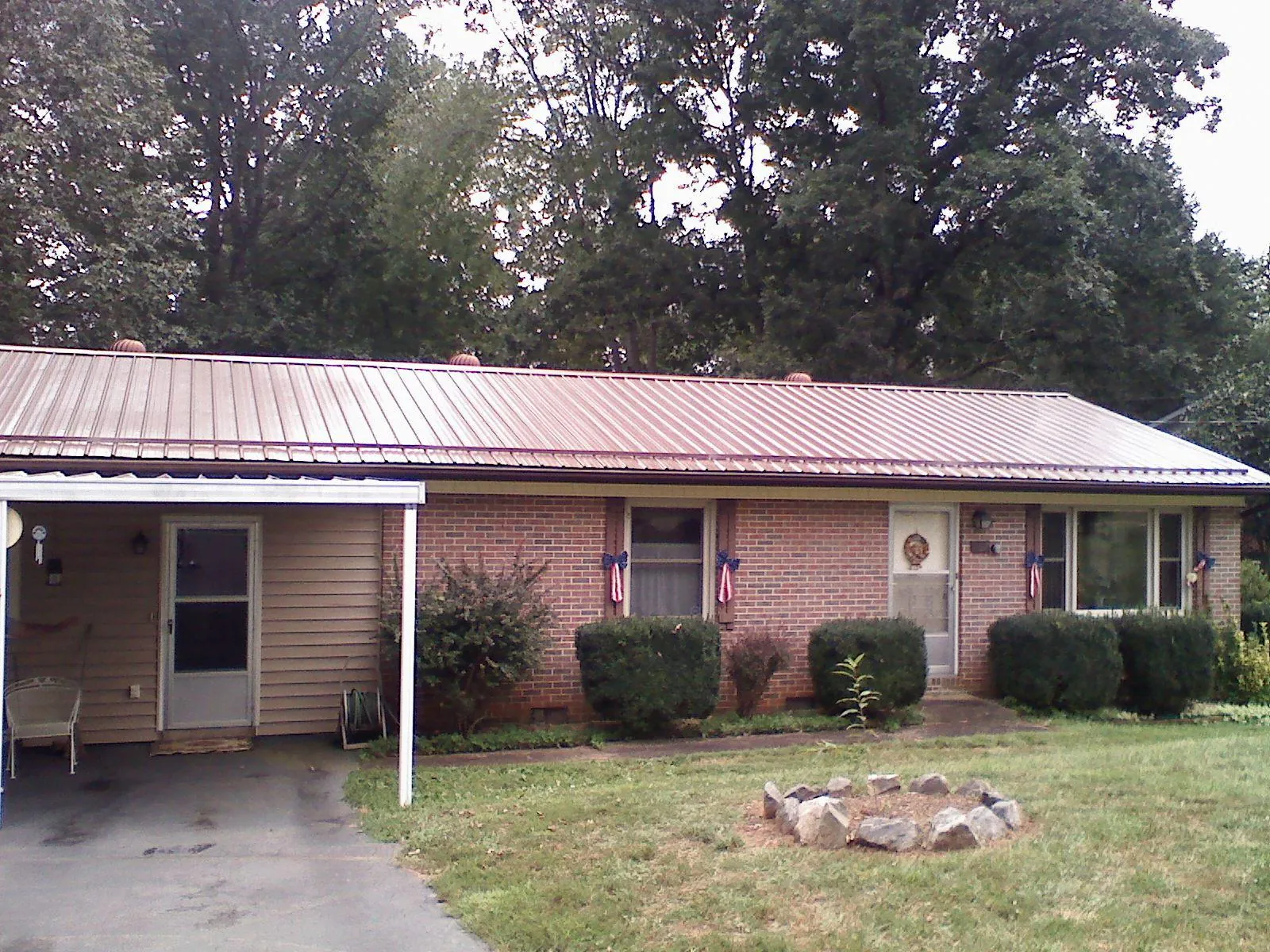 Bronze metal roof and carport on a brick ranch home — Roof Repair work by our crew in Sula