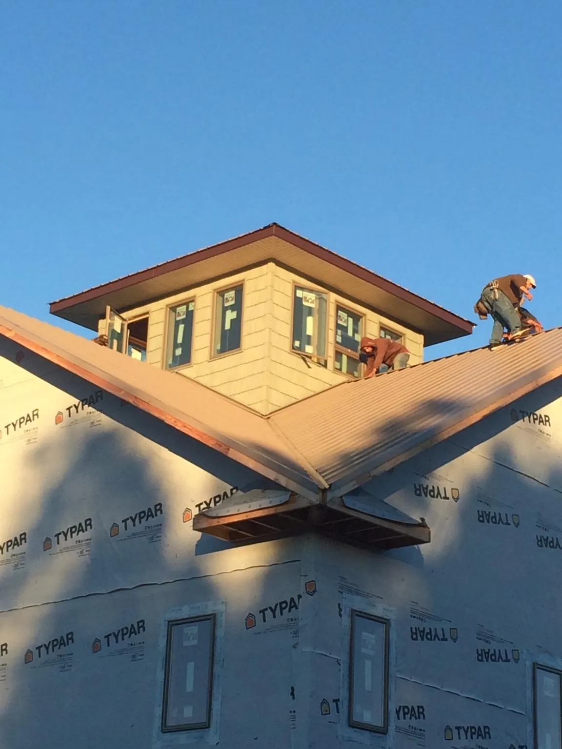 Roofers working around a rooftop cupola on a new metal roof at sunset — Roof Waterproofing in Sula by Roofing Brothers